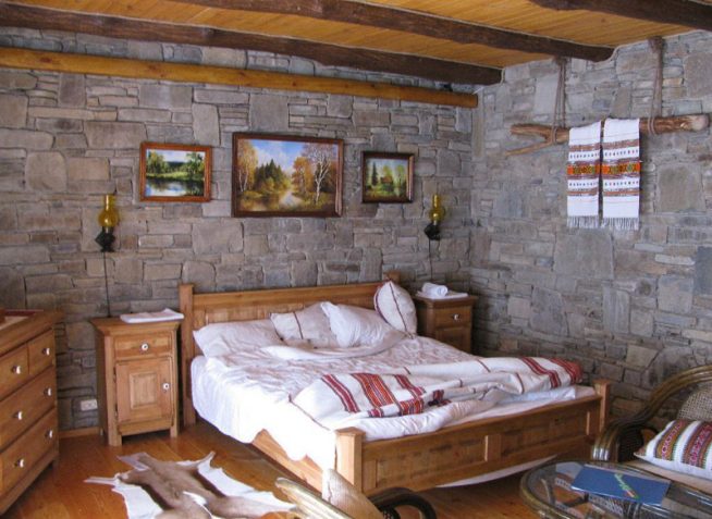 Натуральный камень и потолочные балки в интерьере спальни-шале